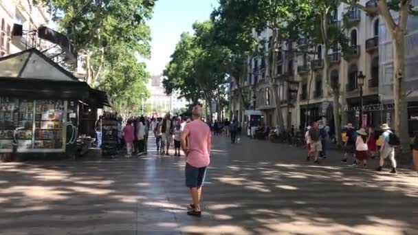 Barcelona, España. 20 de junio de 2019: Un grupo de personas caminando por una calle con La Rambla, Barcelona al fondo — Vídeos de Stock