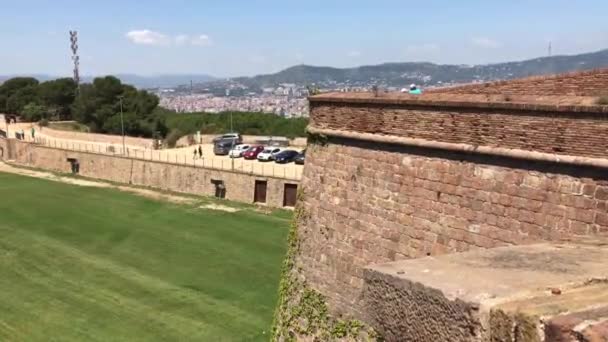 Barcelona, España. Un gran edificio de ladrillo con una montaña en el fondo — Vídeos de Stock