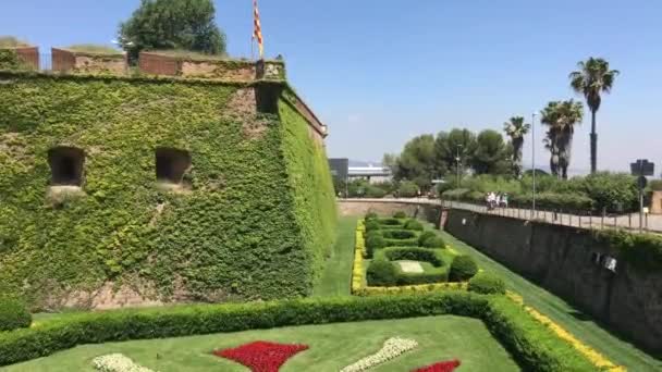 Barcelona, Spanyolország. Egy nagy téglaépület zöld fűvel — Stock videók