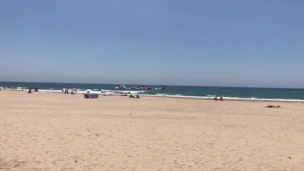 Cambrils, España, 25 de junio de 2019: Un grupo de personas de pie sobre una playa de arena — Vídeos de Stock