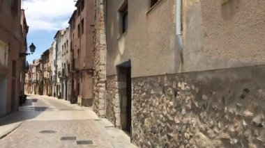 Montblanc, İspanya, arka planda eski binalar olan dar bir şehir caddesi.