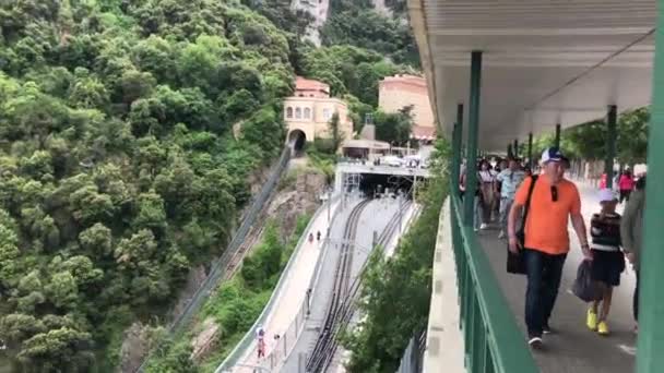 Монсеррат, Испания, 26 июня 2019 г.: Группа людей, путешествующих по железнодорожному пути с деревьями на заднем плане — стоковое видео