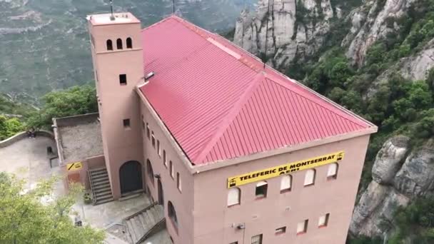 Montserrat, Spanien, Ein großes Backsteingebäude mit einem Berg im Hintergrund — Stockvideo