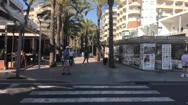 Salou, Hiszpania, Grupa ludzi przechodzących przez ulicę przed budynkiem — Wideo stockowe