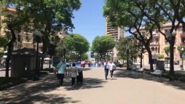 Tarragona, İspanya, 30 Haziran 2019: Bir grup insan caddede bir ağacın yanında yürüyor
