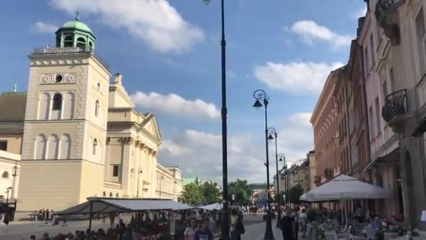 Warszawa, Polonia, Un grupo de personas caminando por una calle junto a edificios altos — Vídeo de stock