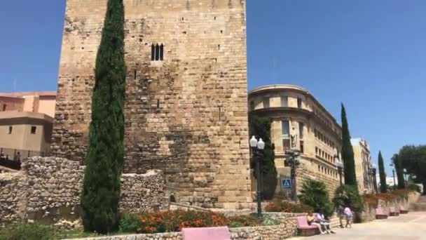 Tarragona, España, Un castillo con una torre de reloj frente a un edificio de ladrillo — Vídeos de Stock