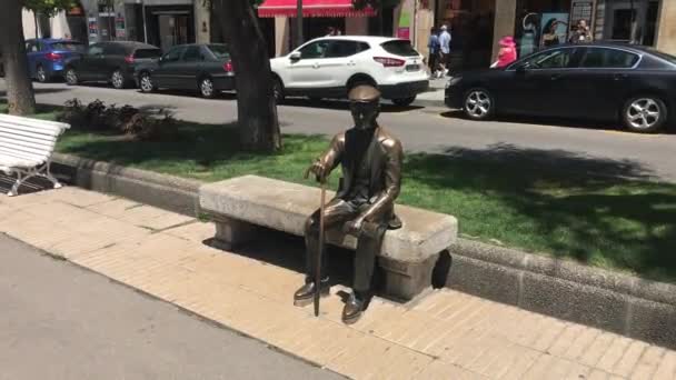 Tarragona, Spanien, 30 juni 2019: En person som sitter på en bänk bredvid en bil — Stockvideo