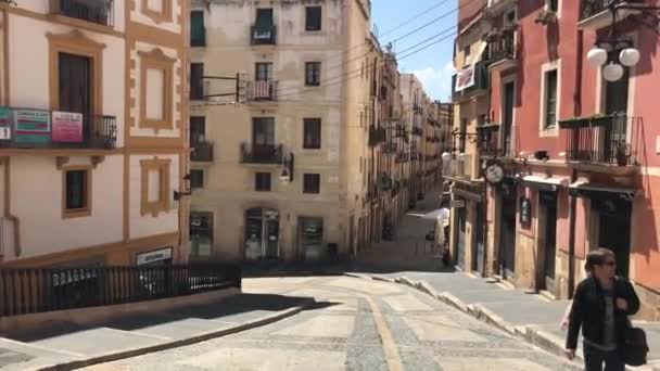 2018 년 6 월 30 일에 확인 함 . Tarragona, Spain, June 30, 2019: 한 사람이 건물 앞에서 길을 걷고 있다 — 비디오