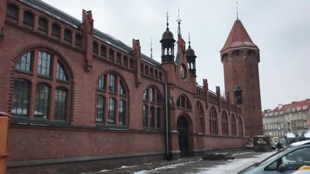 Gdansk, Polonia, Un gran edificio de ladrillo con un reloj en el lado de la calle — Vídeo de stock