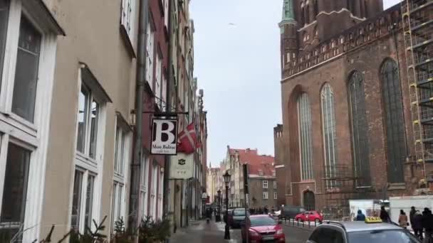 Ґданськ, Польща, Вузька міська вулиця з автомобілями, припаркованими на стіні будинку. — стокове відео