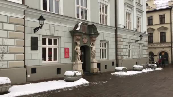 Cracovia, Polonia, Una casa cubierta de nieve frente a un edificio — Vídeo de stock