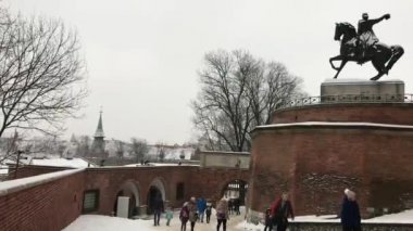 Krakow, Polonya, bir grup insan bir binanın önünde yürüyor.