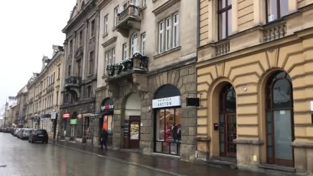 Krakkó, Lengyelország, egy csoport ember sétál az utcán egy épület előtt. — Stock videók