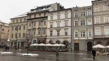 Krakow, Polonya, bir grup insan bir binanın önünde yürüyor.