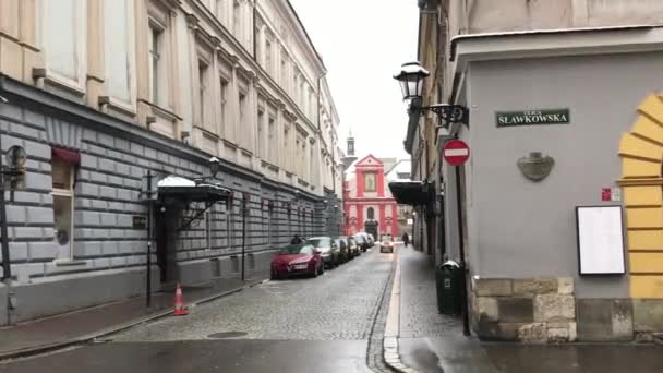 Cracovia, Polonia, 20 de febrero de 2017: Una calle estrecha con coches aparcados al lado de un edificio — Vídeo de stock