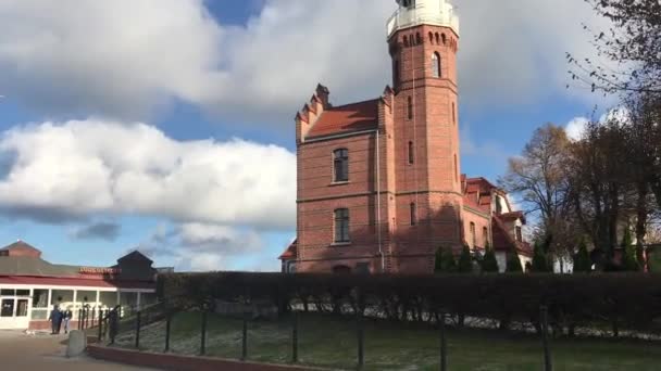 Ustka, Polonia, Una piccola torre dell'orologio di fronte a un edificio in mattoni — Video Stock