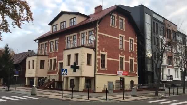 Ustka, Polen, Ein großes Backsteingebäude mit einem Geschäft an der Ecke einer Straße — Stockvideo