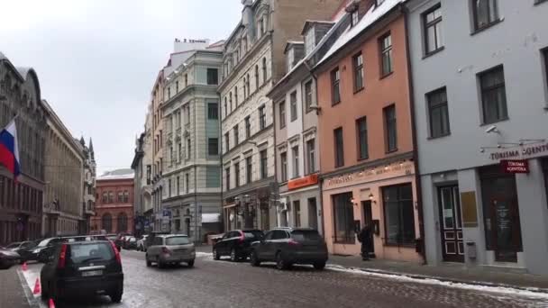 Riga, Letonia, Una calle estrecha de la ciudad con coches estacionados en el lado de un edificio — Vídeo de stock