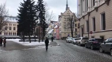 Riga, Letonya, bir grup insan binanın önünde karşıdan karşıya geçiyor.
