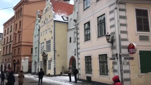 Riga, Letónia, Um grupo de pessoas a caminhar em frente a um edifício — Vídeo de Stock