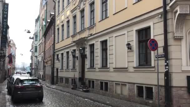Riga, Lettország, egy keskeny városi utca, egy épület oldalán parkoló autókkal — Stock videók