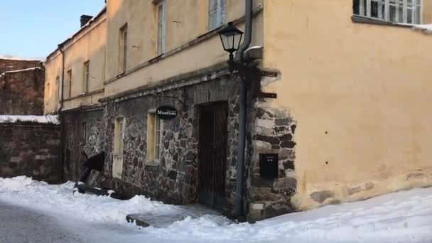 Helsinki, Finlandia, Una casa cubierta de nieve frente a un edificio — Vídeo de stock