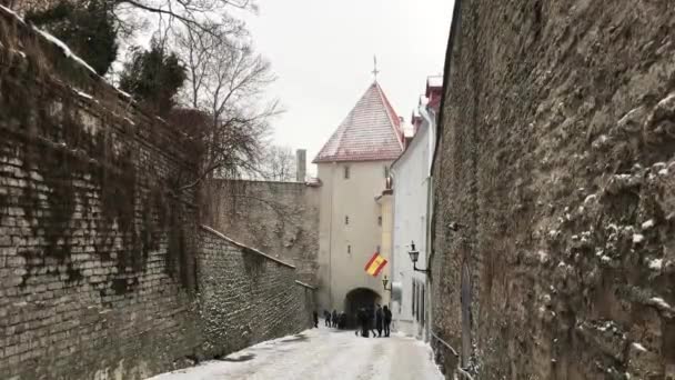 Tallinn, Estónia, Uma pessoa a descer uma rua ao lado de uma parede de pedra — Vídeo de Stock