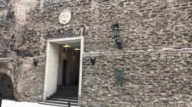 Tallinn, Estonya, taş duvarın tepesinde saati olan büyük bir tuğla bina.