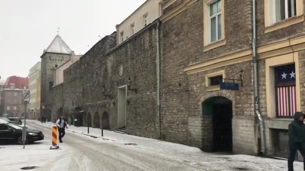 Tallinn, Estonya, bir binanın önündeki caddede yürüyen bir adam. — Stok video