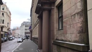 Riga, Letonya, bir binanın yan tarafında binaları olan dar bir şehir caddesi.
