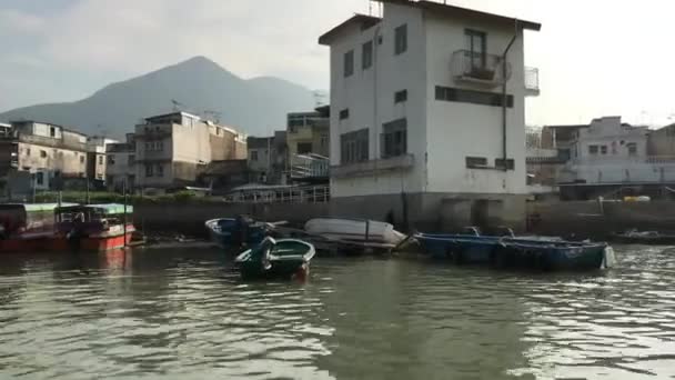 Hong Kong, Kína, egy kis hajó egy víztestben épületekkel a háttérben — Stock videók