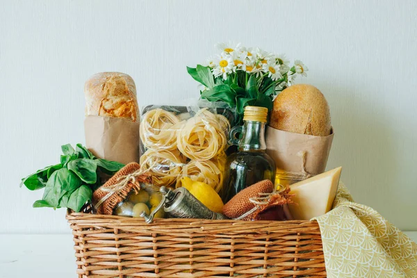 İtalyan gıda sepeti ciabatta ekmeği, tagliatelle, fesleğen, zeytinyağı, bir mason kavanoz, limon, peynir, biber fabrikasında, peçete ve chamomiles bir buket Marine zeytin ile.
