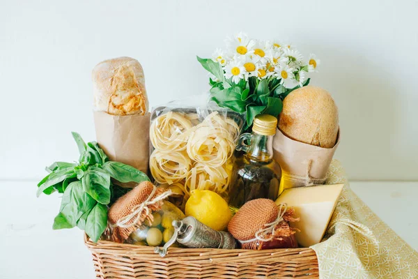 İtalyan gıda sepeti ciabatta ekmeği, tagliatelle, fesleğen, zeytinyağı, domates sosu ve bir mason kavanoz, limon, peynir, biber fabrikasında, peçete ve chamomiles bir buket Marine zeytin ile.