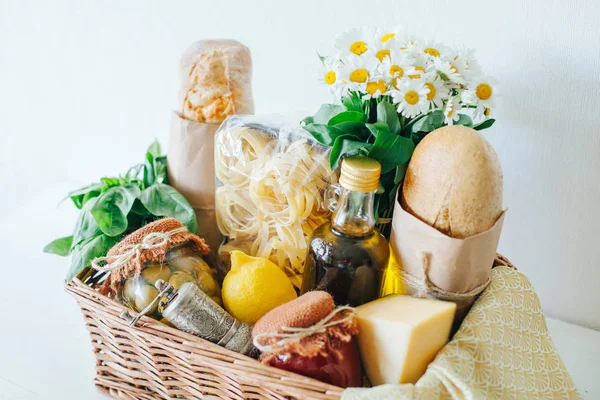 İtalyan gıda sepeti ciabatta ekmeği, tagliatelle, fesleğen, zeytinyağı, Salamura Zeytin ve domates sosu bir mason kavanoz, limon, peynir, biber fabrikasında, peçete ve chamomiles bir buket ile.