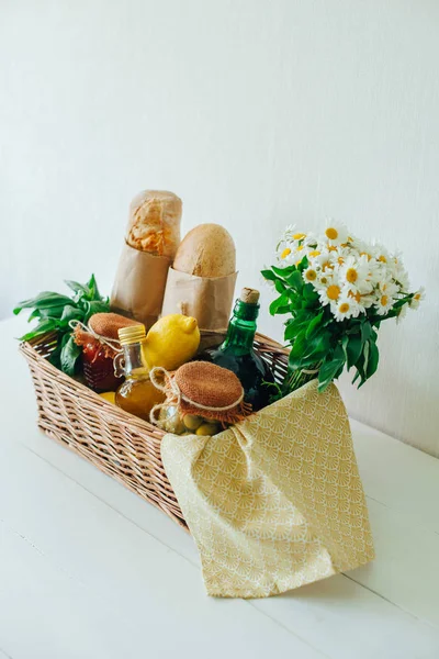 İtalyan gıda sepeti ciabatta ekmeği, fesleğen, zeytinyağı, Marine zeytin ve domates sosu bir mason kavanoza, limon, bir şişe şarap, peçete ve chamomiles bir buket ile.