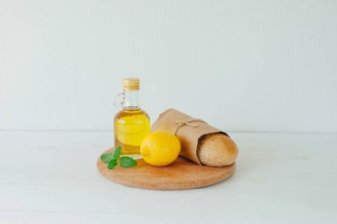 İtalyan ürünleri. Ekmek, zeytin yağı, limon ve Yeşil fesleğen yuvarlak ahşap kesme tahtası üzerinde şişe.