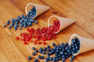 Orman meyve çilek dondurma koni eski rustik beyaz ahşap tablo içinde. Farklı yaz meyveleri. Kırmızı ve mavi çilek. Sağlıklı beslenme. Kahvaltı.