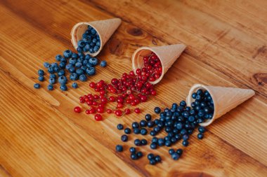 Orman meyve çilek dondurma koni eski rustik beyaz ahşap tablo içinde. Farklı yaz meyveleri. Kırmızı ve mavi çilek. Sağlıklı beslenme. Kahvaltı.