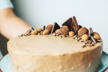 Çikolatalı kek mavi tabakta erkek elinde. Tatlı hediye. Doğum günü. Sevgililer günü. Şef. Homemade Pişirme. Krema ile sünger kek.