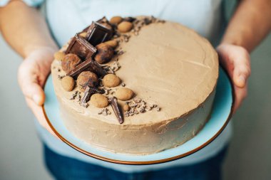 Çikolatalı kek mavi tabakta erkek elinde. Tatlı hediye. Doğum günü. Sevgililer günü. Şef. Homemade Pişirme. Krema ile sünger kek.