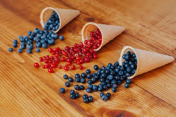 Orman meyve çilek dondurma koni eski rustik beyaz ahşap tablo içinde. Farklı yaz meyveleri. Kırmızı ve mavi çilek. Sağlıklı beslenme. Kahvaltı.