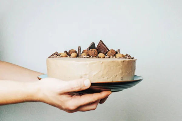 Chocolate cake in male hands on a blue plate. Sweet gift. Birthday. Valentine's Day. Chef. Homemade baking. Sponge cake with cream.