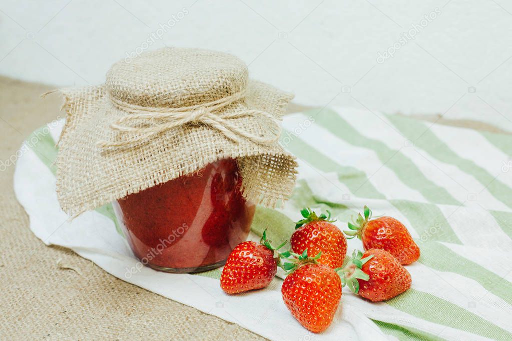 Jar of red strawberry jam on the table