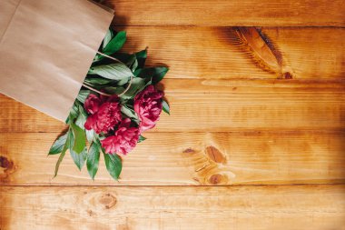 Pembe peonies ahşap masa arka plan üzerinde bir kağıt torba tarafından