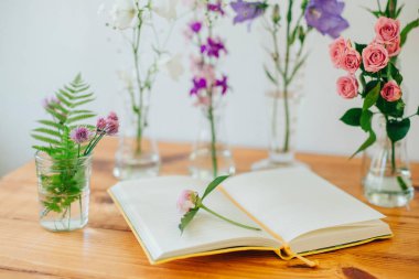 Parfüm örnekleri ve masaya çiçek güzel kompozisyonu. Şişeler çiçeklenir. Kır çiçekleri. Yaz buket. Açık Not defteri. Botanik.