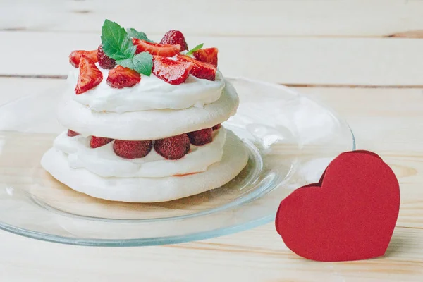 Beyaz tabakta, üstten görünüm Pavlova beze tatlısı. Yuvarlak beze ve çilek üstüne yapılmış tatlı.