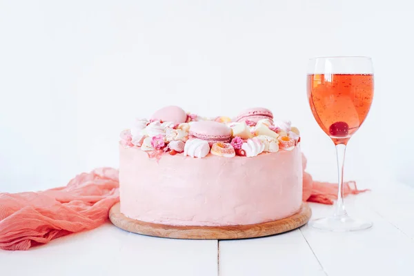 Pink cake. Decoration from sweets, macarons, marshmallows, white chocolate. Sweet birthday present. For girl. Red cocktail. Party.