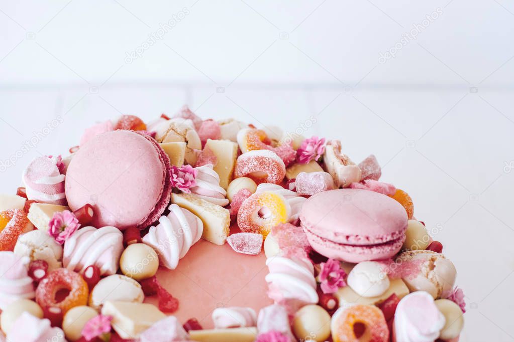 Pink cake. Decoration from sweets, macarons, marshmallows, white chocolate. Sweet birthday present. For girl.
