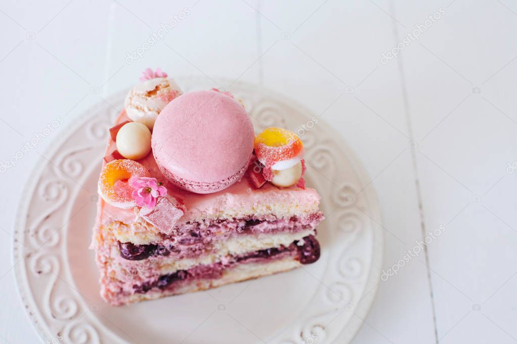 Piece of pink cake. Decoration from sweets, macarons, marshmallows, white chocolate. Sweet birthday present. For girl.